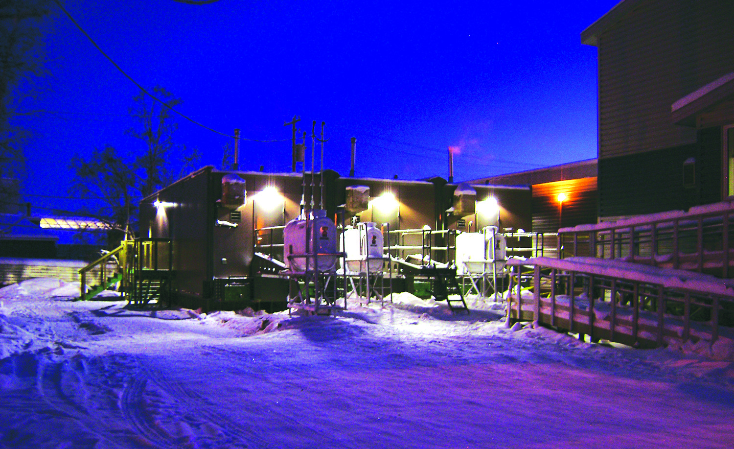 A row of Valid RCMP Holding cell trailers lit up at night in the winter.