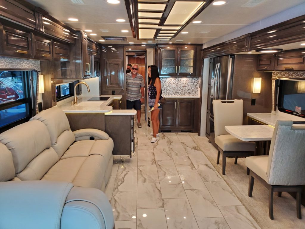 Interior of an RV that has been leveled with an rv leveling system, showing marble floor tiles, beige furniture and dark wood cabinets.
