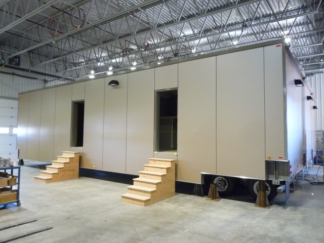 Side view of modular RCMP holding cell trailer with steps leading up to the doors.