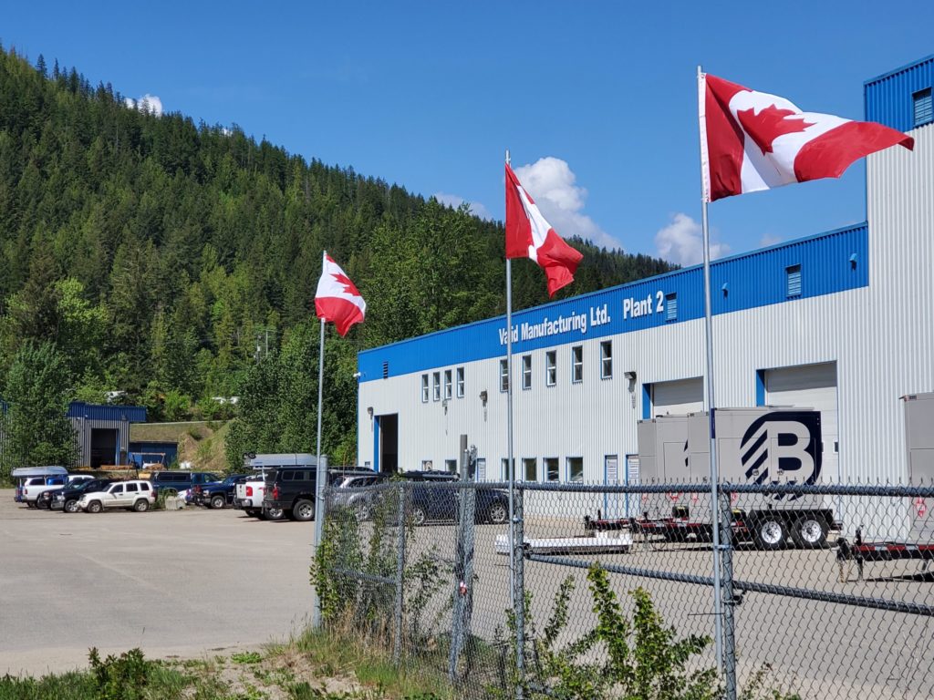 Valid Manufacturing's second on four plants with Canadian flags and employee vehicles parked outside. 