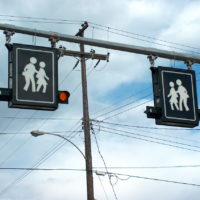 Illuminated Signs for pedestrian crossing hung on a bar.