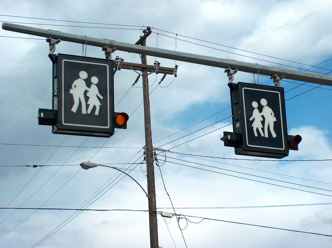 Illuminated Signs for pedestrian crossing hung on a bar.